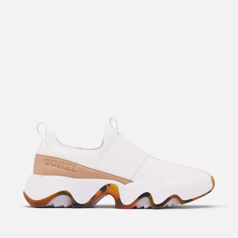 A white sneaker with a tan strap and a multicolored sole featuring shades of orange, brown, and gray.