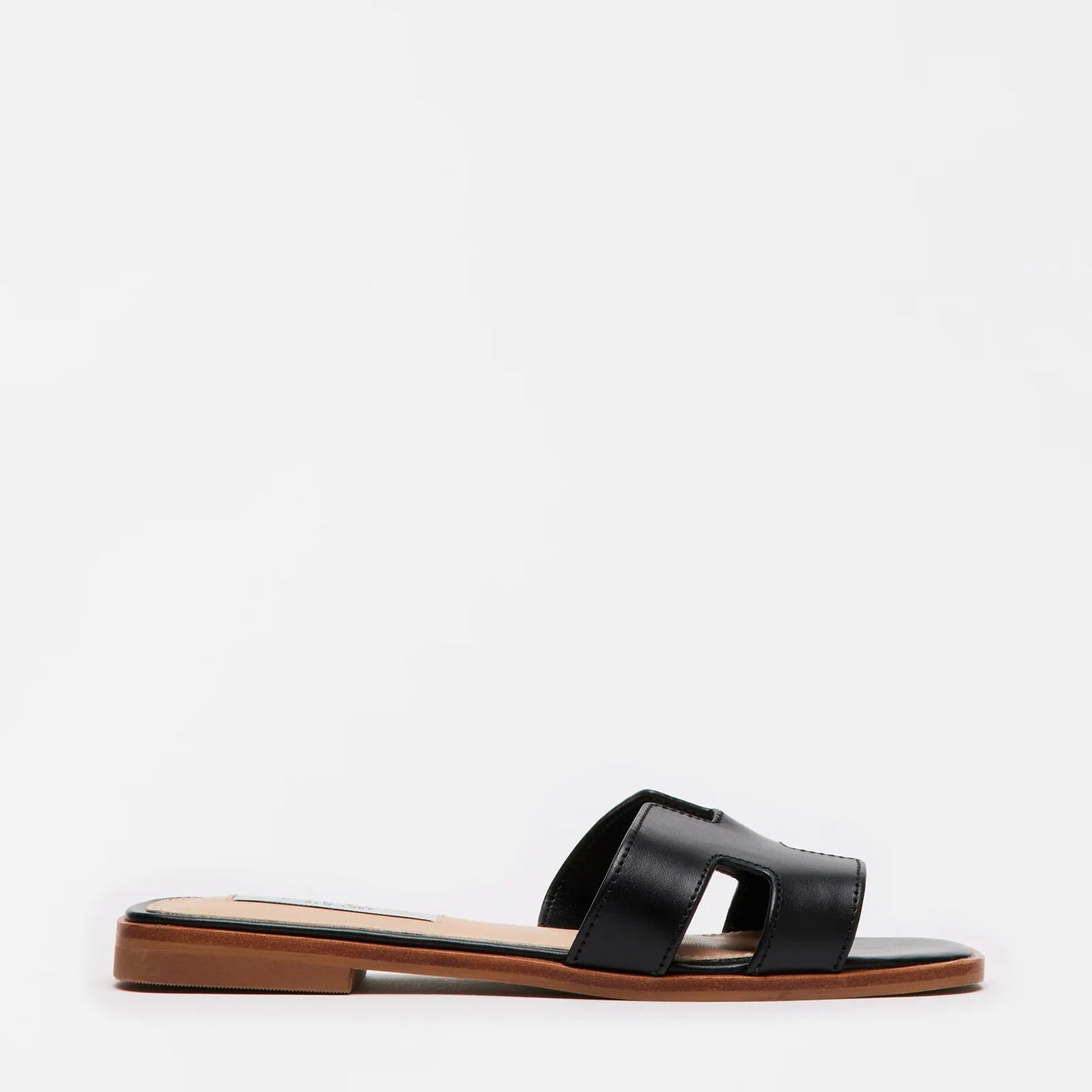 A black flat sandal with geometric cutouts on the strap, placed on a plain background.