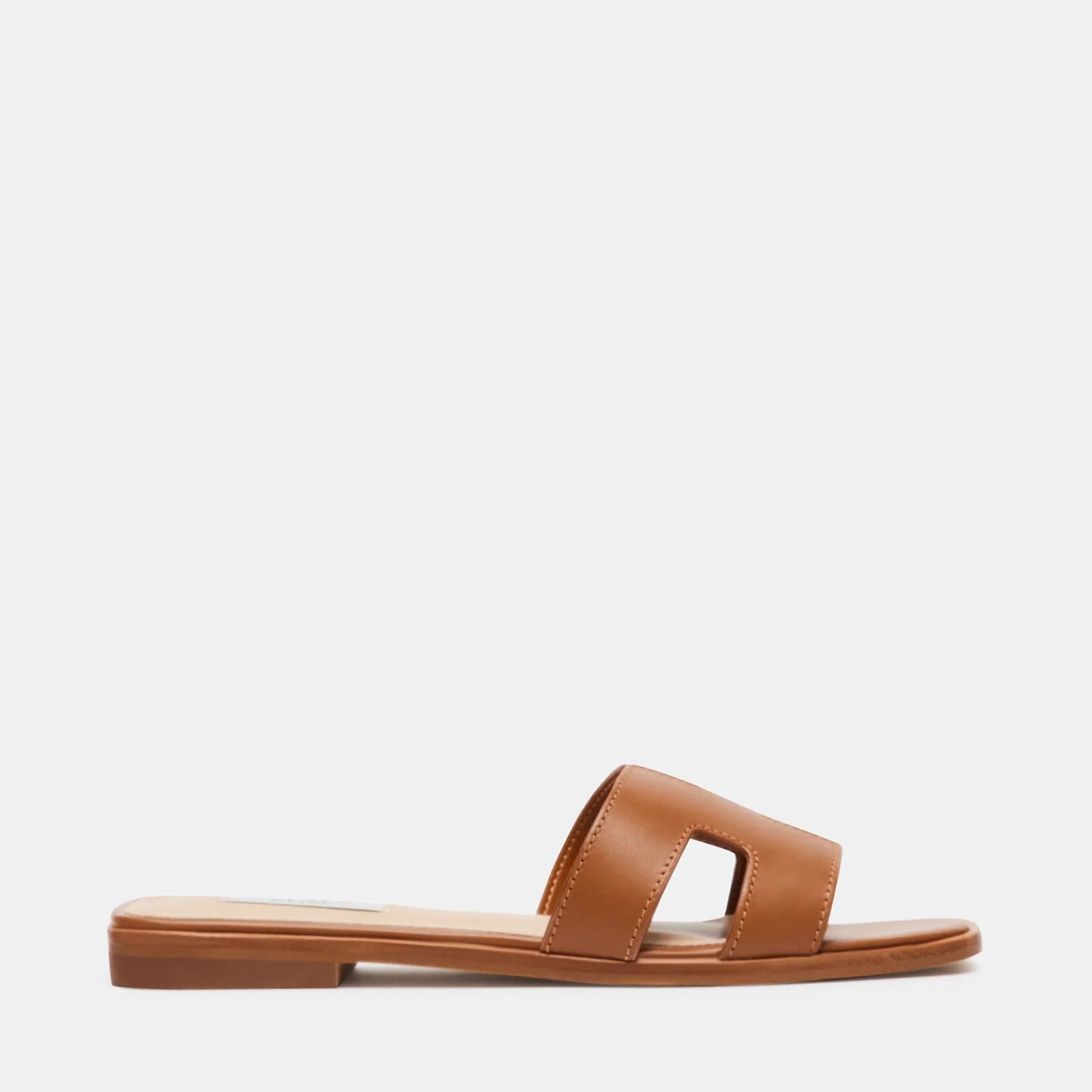 A flat sandal with geometric cutouts on the strap, colored in cognac brown.